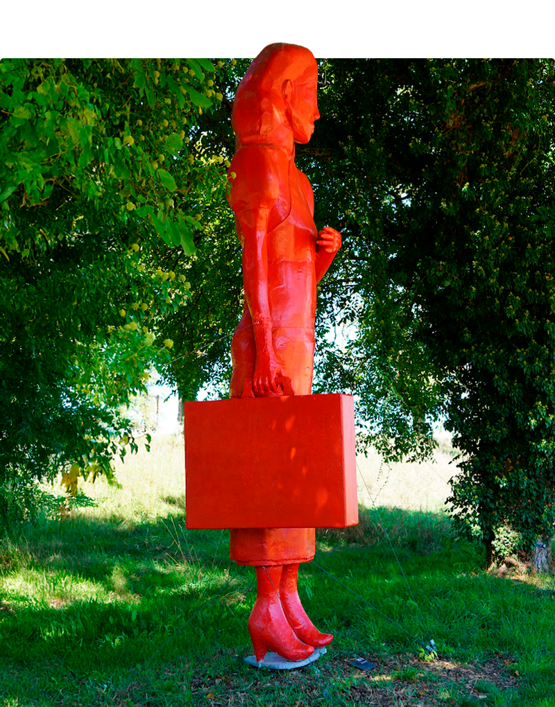 Sculpture représentant une femme valise à la main, en train d'attendre. Elle est toute rouge.