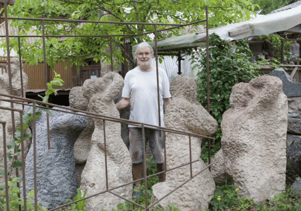 L'artiste Beat Kohlbrenner posant parmi ses oeuvres en pierre.