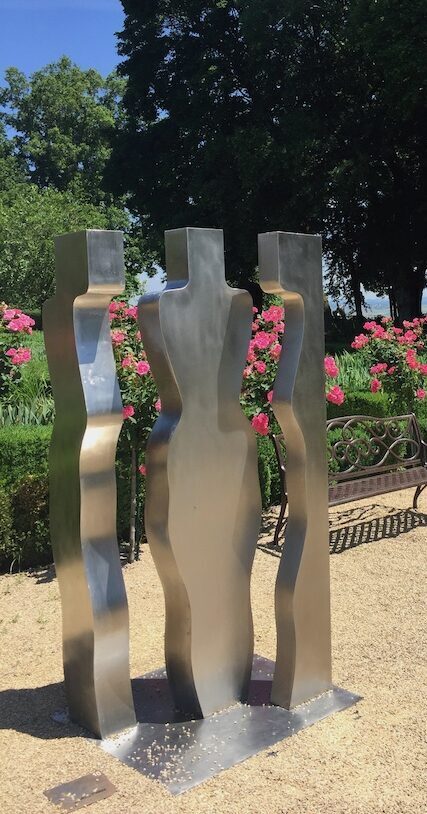 Sculpture contemporaine, représentant 3 femmes, de couleur grise métallique, à découvrir dans le jardin de Doreen au Château de Vullierens.