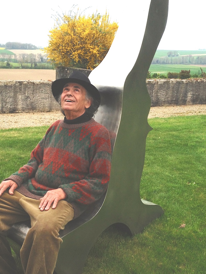 Portrait de l'artiste Manuel Torres assis sur une de ses oeuvres au Château de Vullierens.