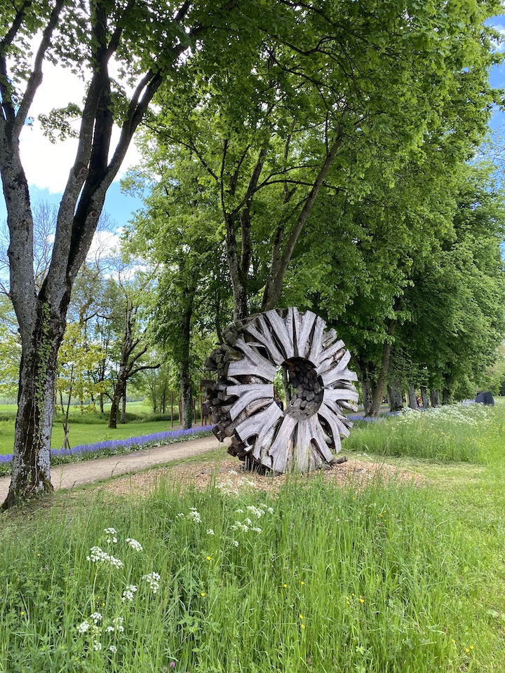 Sculpture en bois tranché par Urs Twellmann dans les jardins du Château de Vullierens en pleine floraison.
