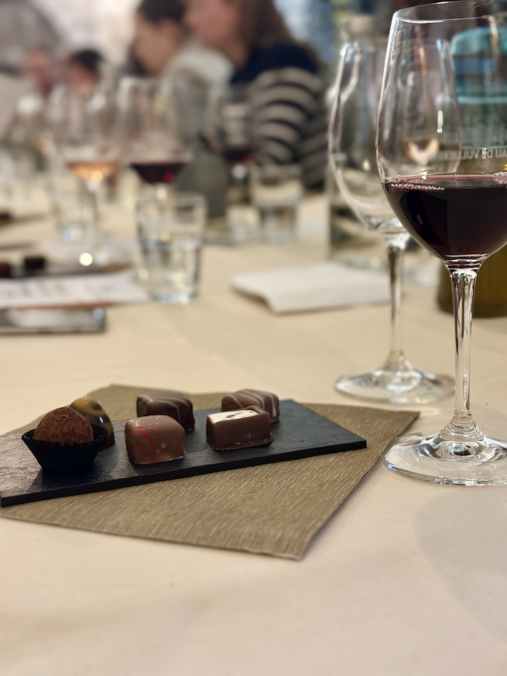Photo rapprochée de la dégustation Vins et Chocolat dans la cave privée du Château. On y voit un verre de vin rouge et 6 truffes.