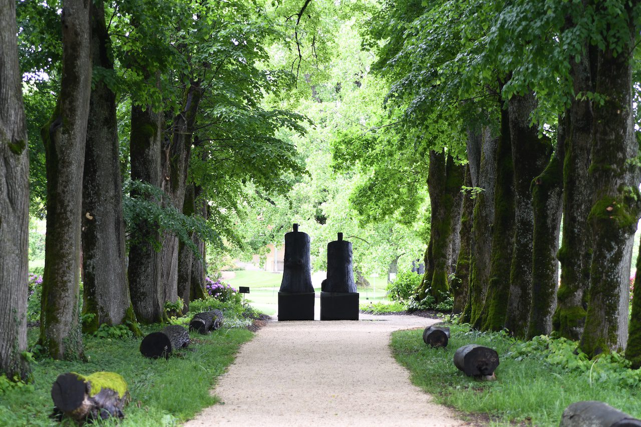 L'allée cavalière du Château de Vullierens au printemps : les couleurs sont vertes foncées, les branches des arbres remplies des belles feuilles vertes et l'atmosphère est lumineuse.