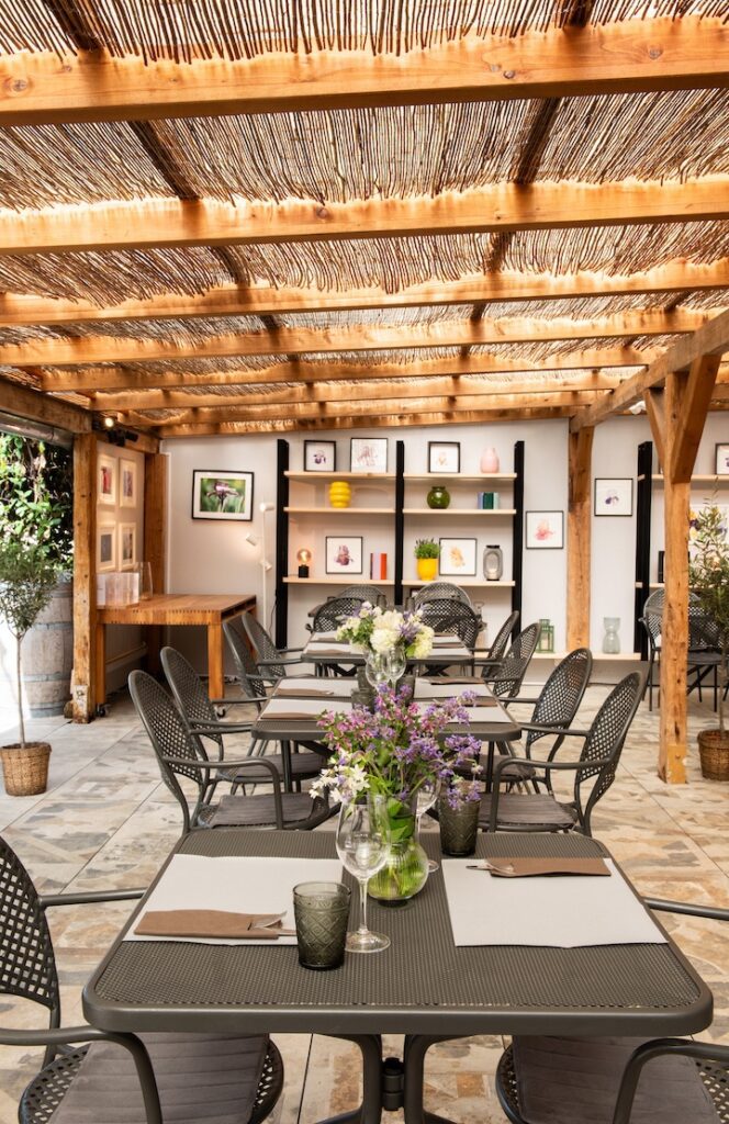 Le Café des Jardins avec tables dressées à l'intérieur sous la pergola.