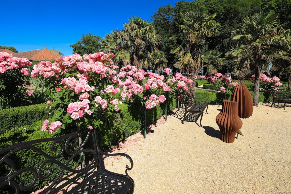 Deux sculptures métallique d'Herbert Mehler exposées dans le jardin de Doreen du Château de Vullierens entourée de rosiers rose en pleine floraison.