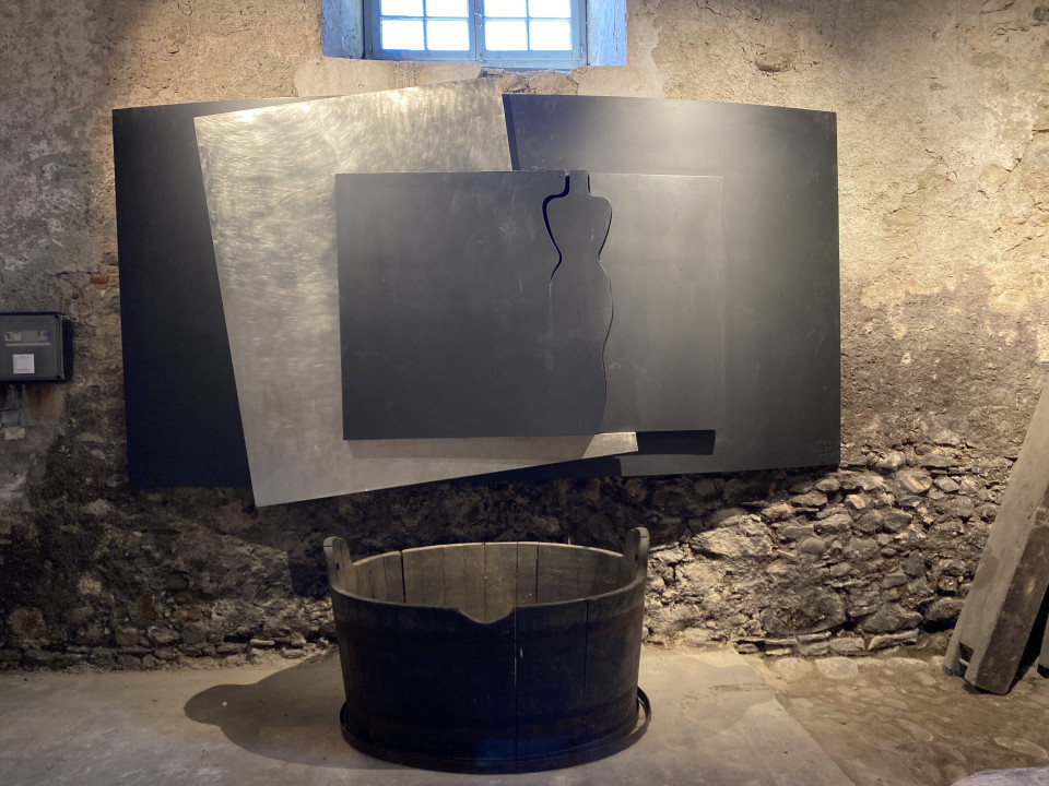 Oeuvre de Manuel Torres à découvrir dans la cave historique du Château de Vullierens, étant une superposition de plusieurs plaques noires et métalique dans lesquelles une femme semble apparaître.