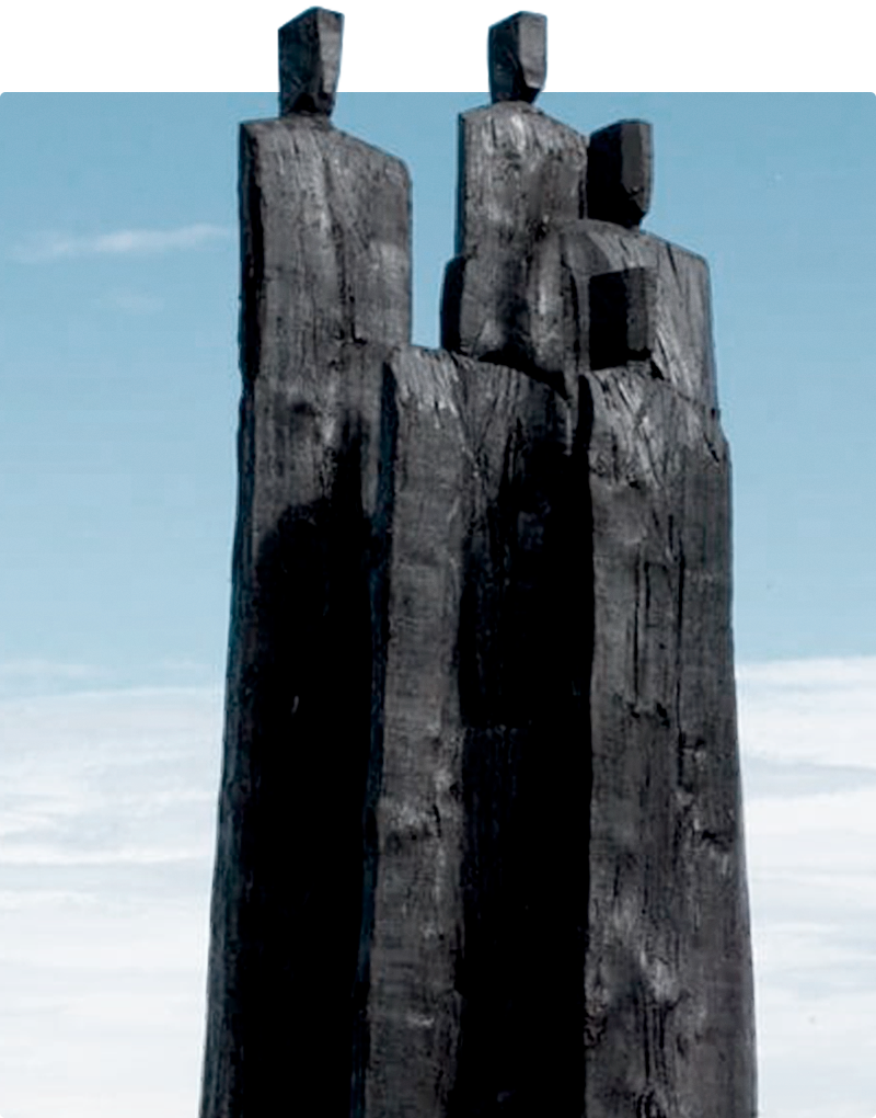 Five charred wooden busts by Christian Lapie against a blue sky backdrop.