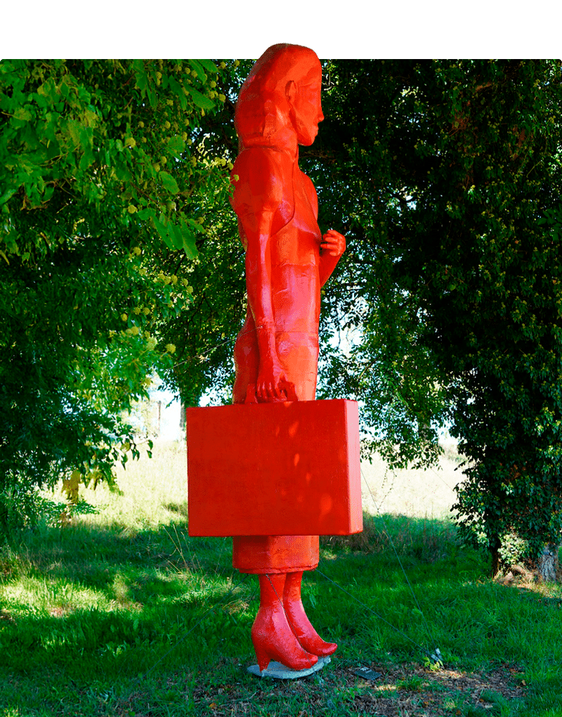 Sculpture depicting a woman with a suitcase in her hand, waiting. She is completely red.