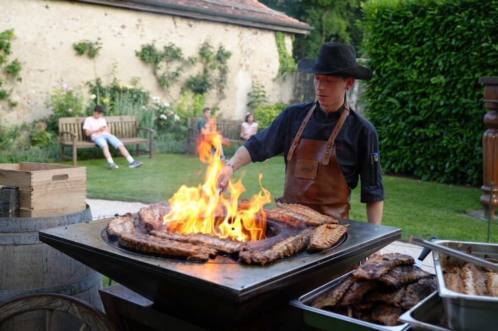 Le Chef en train de griller des viandes lors de la soirée Barbecue au Café des Jardins, sur la terrasse.